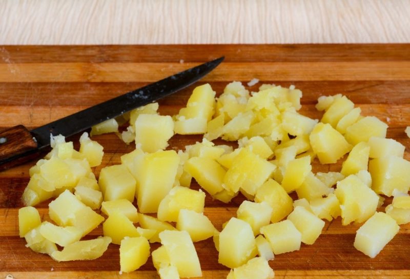 Заранее отварите картофель в кожуре до готовности, далее охладите, очистите и нарежьте средними кубиками.
